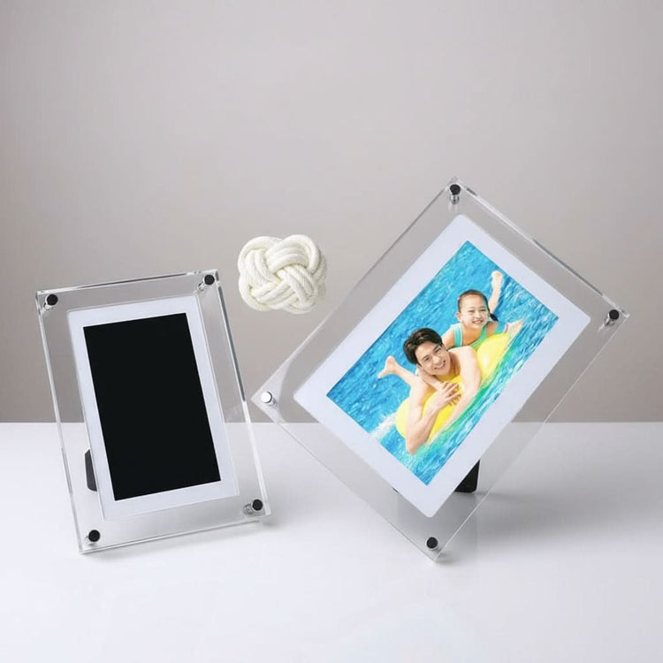 Two clear acrylic photo frames on a white surface with a gray background