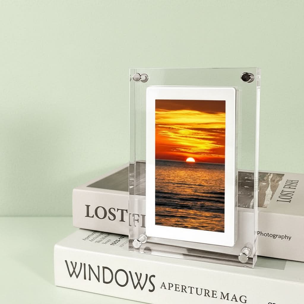 Digital photo frame displaying a sunset image on top of books with &