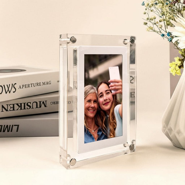 Clear acrylic photo frame with a picture of two women on a desk with books and a vase.