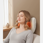 Woman using a massage pillow in a cozy room with a window.