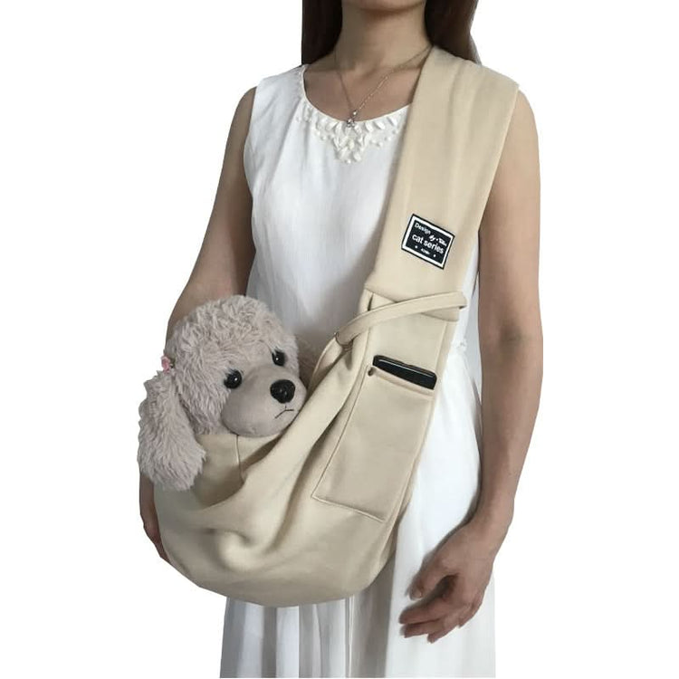 Person holding a beige pet sling with a teddy bear inside on a white background
