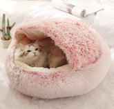 Cat lying in a fluffy pink pet bed on a light background