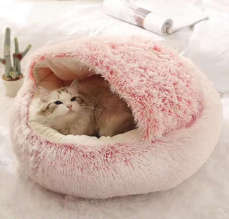 Cat lying in a fluffy pink pet bed on a light background