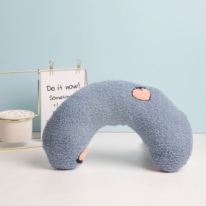 blue fuzzy U-shaped pillow with pink heart on a light blue background