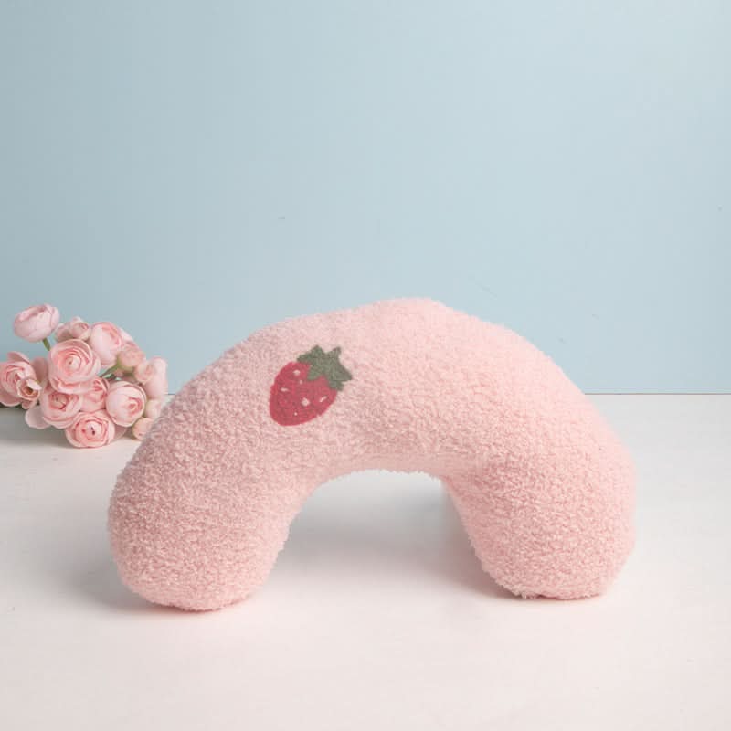 Pink neck pillow with a strawberry design on a light blue background