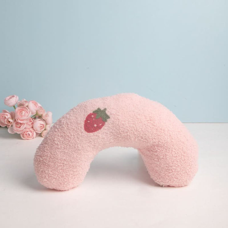 Pink neck pillow with a strawberry design on a light blue background