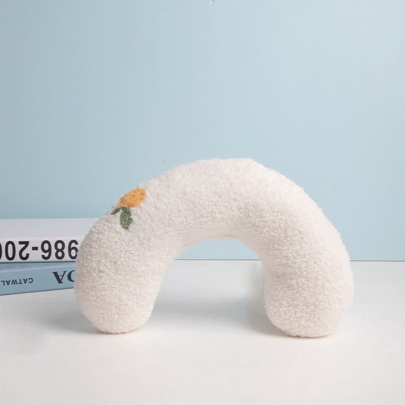 White neck pillow with floral design on a light blue background