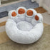 Plush paw-shaped pet bed with soft gray fur and brown paw accents on a rug