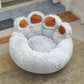 Plush paw-shaped pet bed with soft gray fur and brown paw accents on a rug