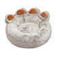 Plush round pet bed shaped like a paw, soft beige fur with brown accents, cozy design.