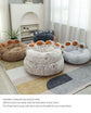 Plush pet beds shaped like animal paws in neutral colors on a cozy rug in a bright room.