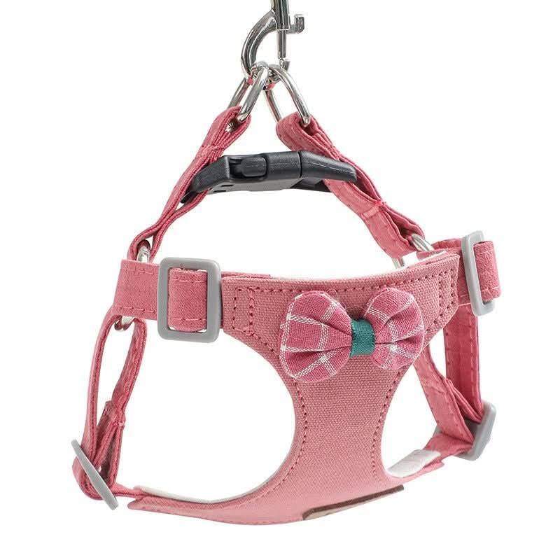 Pink adjustable dog harness with plaid bowtie detail and metal clip attachment.