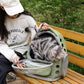Person sitting on a bench with a cat in a green pet carrier, outdoors. Pawsifypets 