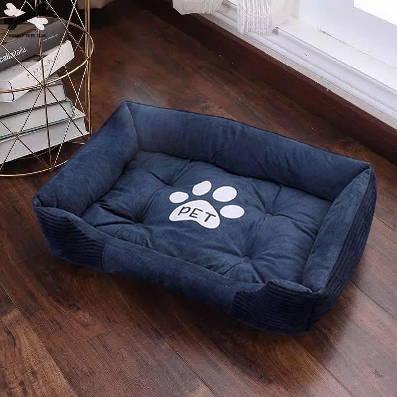 Navy blue plush pet bed with raised sides and paw print for dogs or cats on wooden floor
